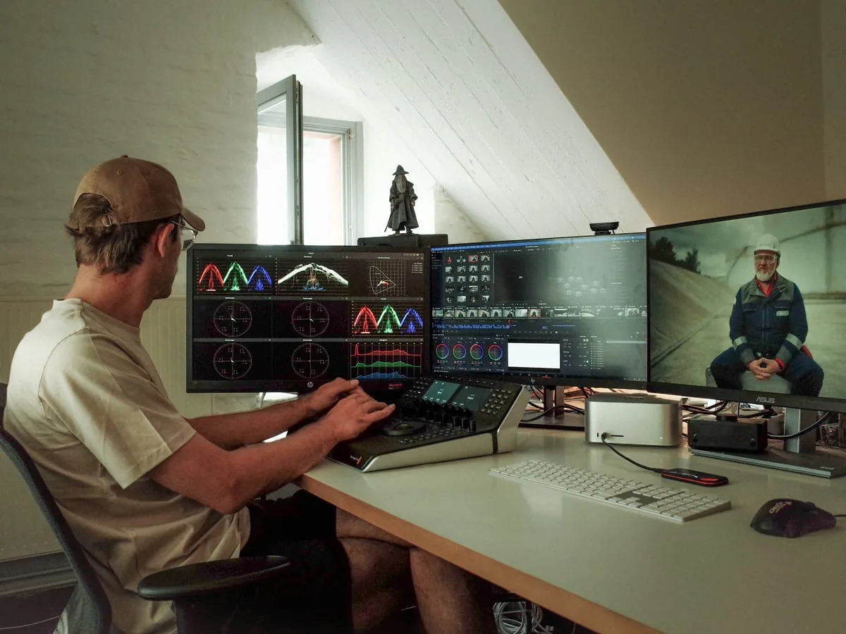 Farbkorrektur im Studio Köln Farbkorrektur unter der Dachschräge: ein Mann am Bedienpult vor drei Monitoren mit Messkurven, Schnittprogramm und Standbild